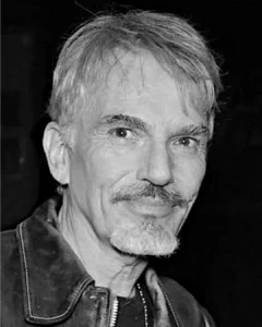 "Black and white portrait photo of Billy Bob Thornton with mustache and goatee wearing leather jacket looking directly at camera