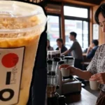 Iced coffee drink with Kohiko Coffee House logo served by Japanese barista in traditional clothing at Sugar Land cafe