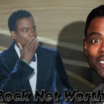 Chris Rock in blue velvet tuxedo at the Oscars ceremony, representing his $60 million net worth and entertainment career