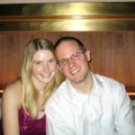 A smiling couple sitting closely together in a warm wooden interior.