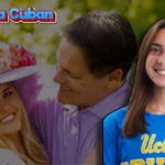 Photo of Alyssa Cuban smiling, wearing a blue UCLA shirt, with a background showing her with her father, Mark Cuban, outdoors with greenery behind them.