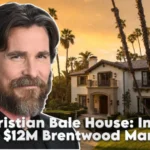 Christian Bale standing in front of his $12M Brentwood mansion in Los Angeles, surrounded by palm trees at golden hour.
