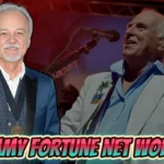 Jimmy Fortune net worth: Country music singer in formal blue blazer and performing at microphone during concert performance