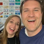 Doug DeMuro and his wife Joanna smiling together in front of vintage license plates, capturing a rare intimate moment of the private couple