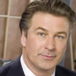 Alec Baldwin net worth — actor Alec Baldwin in a navy suit and white shirt