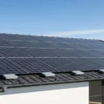 HMS Photovoltaik solar panels installed on modern residential roof with black tiles and clear blue sky