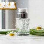 Primerem hydrating primer bottle with pump dispenser surrounded by aloe vera leaves and chamomile flowers on white surface with water droplets